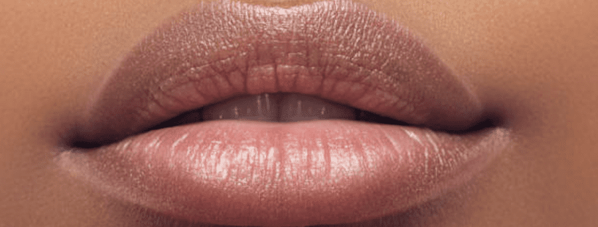 Close-up of neutral-toned, glossy lips.